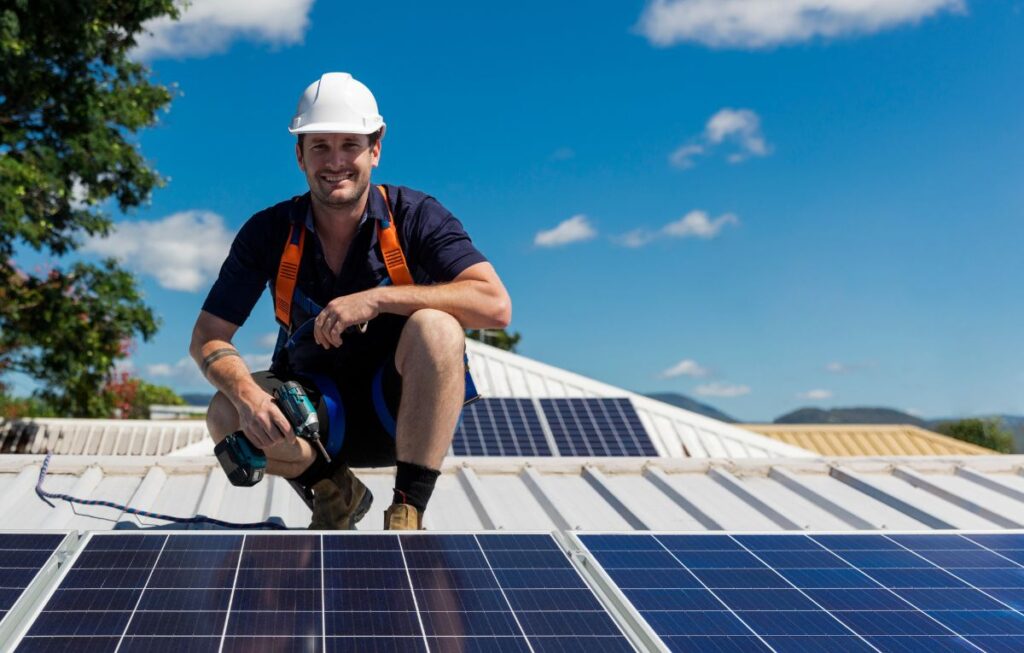 man on top of the roof, behind a solar power.